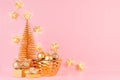 Christmas festive background with golden sparkle decoration in bowl, Christmas tree, glowing garland on pink backdrop. Royalty Free Stock Photo