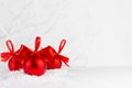 Christmas festive background in white and red color - group of red shimmer balls with satin ribbon, bows in snowdrift under white. Royalty Free Stock Photo