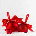 Christmas festive background in white and red color - group of red shimmer balls with satin ribbon, bows in snowdrift under white. Royalty Free Stock Photo