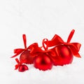 Christmas festive background in white and red color - heap of red shimmer balls with satin ribbon, bows in snowdrift under white. Royalty Free Stock Photo