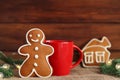 Christmas festive composition. Gingerbread man cookie and house coockie, red cup with tea or coffee, Christmas tree branches with Royalty Free Stock Photo