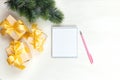 Christmas festive composition. White notepad, pink pen, gifts with a gold bow on a light table. Flat lay, top view Royalty Free Stock Photo