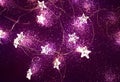 Christmas festive garlands in the shape of a star. Glowing festive bokeh. Purple background for design