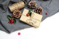 Christmas festive styled stock image composition. Handmade Christmas gift box, red berries, pine cones isolated on grey