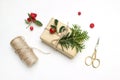 Christmas festive styled stock image composition. Handmade gift box with red berries, fir tree branch, golden scissors