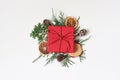 Christmas festive styled stock image composition. Red wrapped gift box, cypres branches, dry apple, orange fruit and