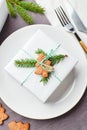 Christmas festive table setting, plate with gift decorated with spruce sprigs and gingerbread Royalty Free Stock Photo