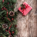 Christmas fir branches on holiday wooden background with gift boxes, pine cones, red decoration. Xmas and New Year theme. Royalty Free Stock Photo