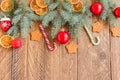 Christmas fir-tree branches with baubles, candy canes, dry oranges and star shape cookies on wooden background with copy space Royalty Free Stock Photo