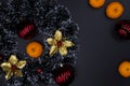 Christmas fir tree decor and tangerines on black background. Winter Holiday season wreath composition Royalty Free Stock Photo