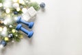 Christmas fitness composition with blue dumbbells, gift on white background with bokeh and show