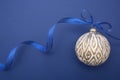 Christmas flat lay. Bauble with blue ribbon, isolated over blue background. Classic blue abstract background. Copy space Royalty Free Stock Photo