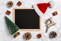 Christmas flat lay: blank blackboard with festive decoration, santa hat, deer, tree and presents on marble background Royalty Free Stock Photo