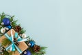 Christmas flat lay composition of fir branches with gift box and decorations with copy space on the blue background. Royalty Free Stock Photo