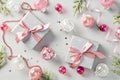 Christmas flat lay composition with gift boxes decorated pink ribbon bows, glitter baubles, fir branches, confetti on grey Royalty Free Stock Photo