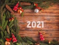 Christmas flat lay concept with new year 2021 text, bells and balls with red ribbon toys and pine strobile tree branches on brown