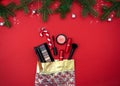 Christmas flat lay with makeup cosmetic products in gift bag on red background. Top view. Beauty banner for sale Royalty Free Stock Photo