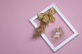 Christmas flat lay on pink background. In white frame ball with gold bow and coniferous twig. Royalty Free Stock Photo