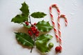 Christmas flat lay scene with two candy canes, green and red holly with ornaments