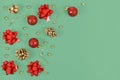 Christmas flat lay with seasonal red tree ornament baubles, gift wrapping bows and golden snowballs on green background Royalty Free Stock Photo