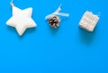 Christmas flat lay, white Christmas tree toy star, pinecone and silver gift box on blue background Royalty Free Stock Photo