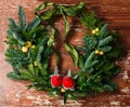 Christmas floral wreath decoration with baubles, red bow, holly and winter greenery over oak background. Royalty Free Stock Photo