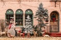 Christmas forest tableau with snowman and be-ribboned deer outside windows of pink stucco house Royalty Free Stock Photo