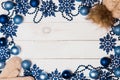 Christmas frame of blue balls, beads, stars and warm knitted hats and mittens on a white table, top view Royalty Free Stock Photo