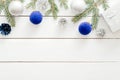 Christmas frame border made of blue and silver decorations, balls, gift boxes, pine tree branch on white wooden background. Flat Royalty Free Stock Photo