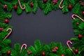 Christmas frame border wirh fir branch, candy cane and baubles on black background