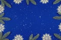 Christmas frame composition, twigs and snowflakes on a blue background and snow, copy space, top view