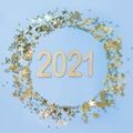 Christmas frame with date New 2021 Year and golden glitter confetti stars on blue. Xmas circle border. Royalty Free Stock Photo