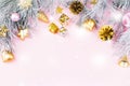 Christmas border with fir branches, conifer cones, christmas balls and golden christmas ornaments on pastel background Royalty Free Stock Photo