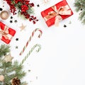 Christmas frame flat lay with pine, red presents, golden elements, candy canes, confetti. Christmas template on white background. Royalty Free Stock Photo