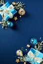 Christmas frame of gift boxes, glistering Xmas balls ornaments, fir tree branches on dark blue background. Happy New Year party Royalty Free Stock Photo