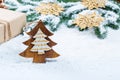 Christmas frame with gift, the branches of the Christmas tree and wooden decorations on snow background Royalty Free Stock Photo
