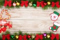 Christmas frame made of fir branches decorated with balls, bows, candy canes and boxes on a light wooden background Royalty Free Stock Photo