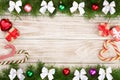 Christmas frame made of fir branches decorated with balls, bows, candy canes and boxes on a light wooden background Royalty Free Stock Photo