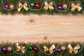 Christmas frame made of fir branches decorated with golden bows beads and balls on a light wooden background Royalty Free Stock Photo