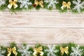 Christmas frame made of fir branches decorated with snowflakes and gold bows on a light wooden background Royalty Free Stock Photo