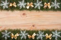 Christmas frame made of fir branches decorated with snowflakes and gold bows on a light wooden background Royalty Free Stock Photo