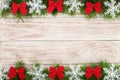 Christmas frame made of fir branches decorated with snowflakes and red bows on a light wooden background Royalty Free Stock Photo