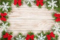 Christmas frame made of fir branches decorated with snowflakes and red bows on a light wooden background Royalty Free Stock Photo