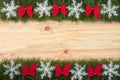 Christmas frame made of fir branches decorated with snowflakes and red bows on a light wooden background Royalty Free Stock Photo