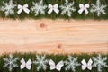 Christmas frame made of fir branches decorated with snowflakes and white bows on a light wooden background Royalty Free Stock Photo