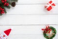 Christmas frame made of fir branches, holly berry and red gift box with decoration on white wood board. Royalty Free Stock Photo