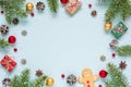 Christmas frame made of fir branches, red berries, gift boxes and pine cones on blue background Royalty Free Stock Photo