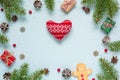 Christmas frame made of fir branches, red berries, gift boxes and pine cones with knitted heart Royalty Free Stock Photo