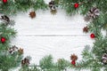 Christmas frame made of fir branches, star anise, decorations and pine cones on white wooden table covered with snow Royalty Free Stock Photo