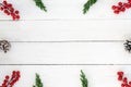 Christmas frame made of fir leaves, pine cones and holly berry decoration rustic elements on white wooden. Royalty Free Stock Photo